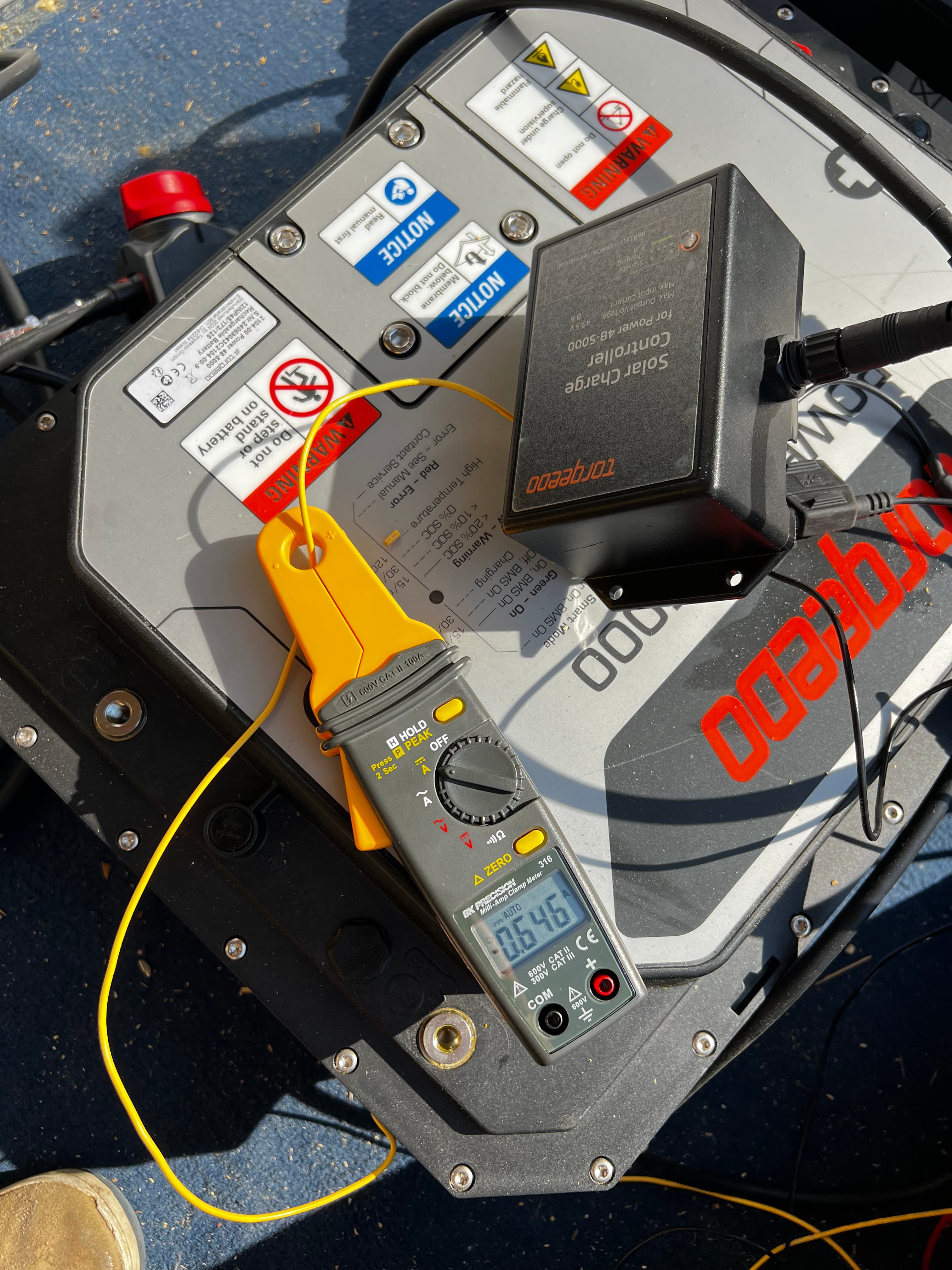 Person sitting on finished roof with two large solar panels laid out on either side, lake visible in background